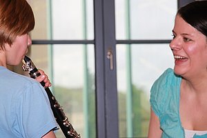 Junge beim Flötespielen mit Musiklehrerin