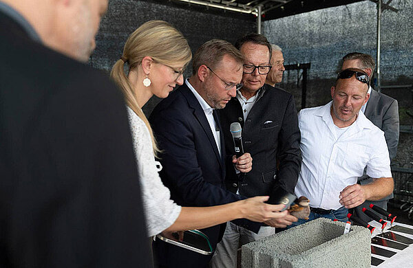 Obürgermeisterin Katrin Albsteiger, Oberbürgermeister Martin Ansbacher und Regierungspräsident Klaus Tappeser legen Gegenstände in den Grundstein.