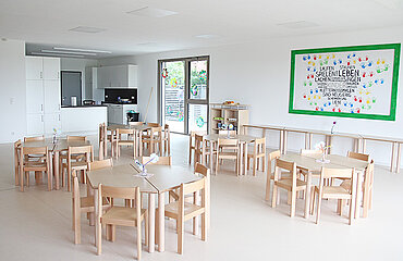 Speiseraum im Kinderhaus mit Tischen, Stühlen und Küche