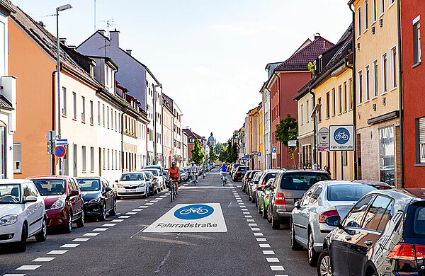 Straße in der Innenstadt mit der Fahrban-Beschriftung "Fahrradstraße" sowie Fahrradfahrern