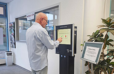 Eine Person meldet sich am digitalen Anmeldeterminal im Bürgerbüro an.