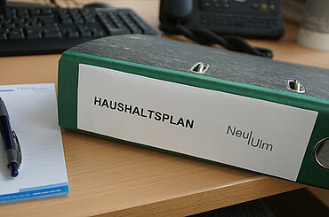 Aktenordner mit der Aufschrift "Haushaltsplan" und dem Logo der Stadt Neu-Ulm