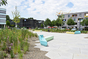 Der neue Stadtteilplatz im Wiley mit gelben, blauen und grünen Sitzbänken