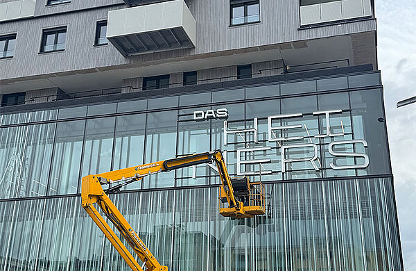 Hebebühne vor dem Schriftzug "Das HEiNERS" an der Fassade des Gebäudes