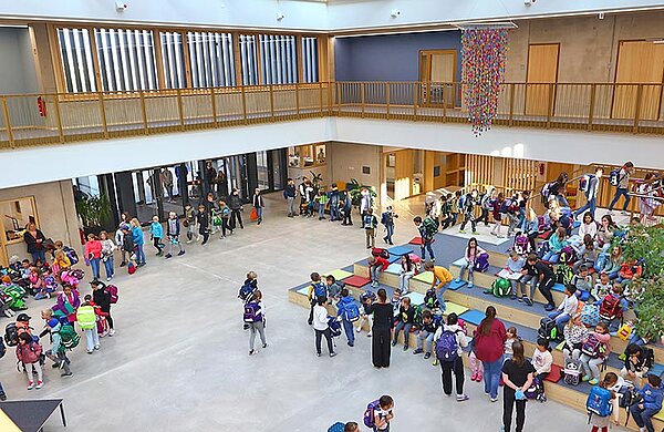 Große Aula der Schule mit Schülerinnen und Schülern