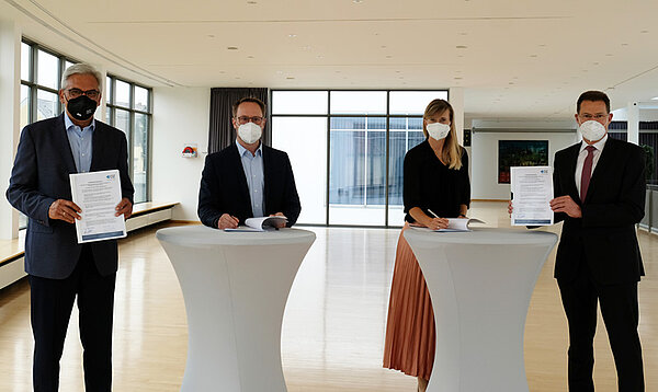 Die genannten Personen an Stehtischen beim Unterzeichnen der Kooperationsvereinbarung