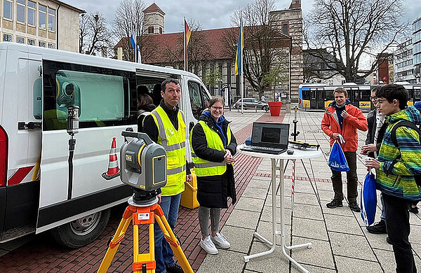 Kollegen der Geoinformation zeigen den Jugendlichen ein Vermessungsgerät.