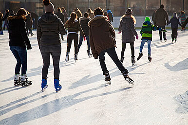 Kinder und Erwachsene beim Schlittschuhlaufen auf der Eislaufbahn