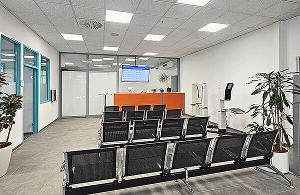 Wartebereich mit Sitzreihen und digitaler Aufrufanzeige