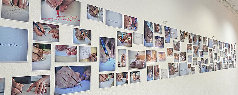 Fotowand mit Bildern von schreibenden Händen