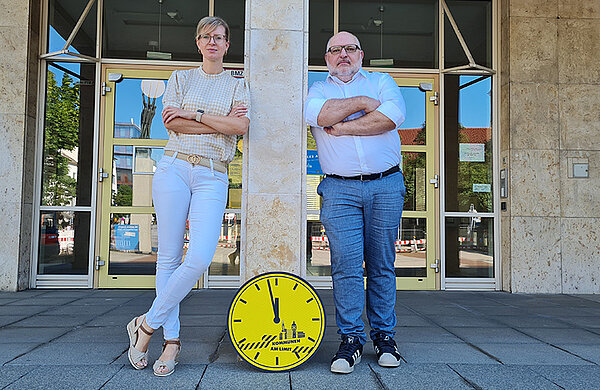 Oberbürgermeisterin Katrin Albsteiger und Stadtkämmerer Gregor Kamp vor dem Rathaus mit einer gelben Uhr