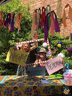 Zwei junge Frauen hinter einem Fotorahmen halten Schilder mit dem Text "Unterschiede gemeinsam feiern"
