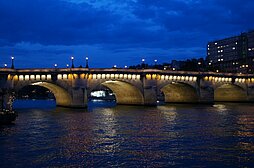 Blick während der Abenddämmerung vom Ufer der Seine auf eine Brücke