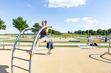 Eine junge Frau macht Klimmzüge an einem Fitnessgerät im Sport- und Freizeitpark Wiley.