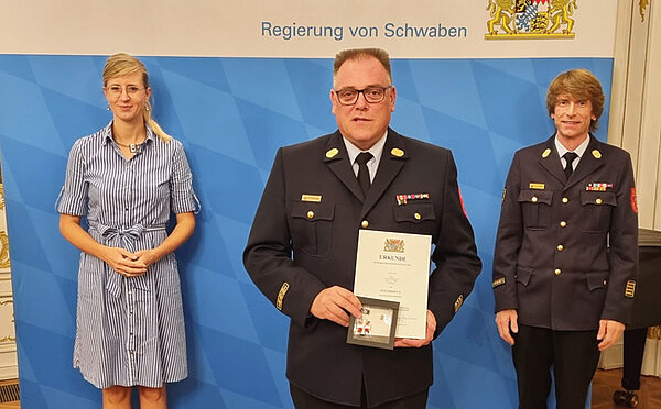 Neu-Ulms Oberbürgermeisterin Katrin Albsteiger, Feuerwehrkommandant Andreas Hoffzimmer mit Urkunde sowie Kreisbrandrat Dr. Bernhard Schmidt schauen in die Kamera