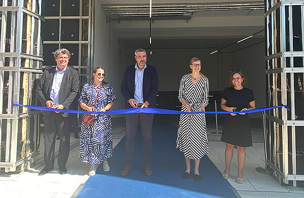 Matthias Orlowski (Rechtsberater der Investoren), Anke Lotko, Frank Bindszus (beide Albrings + Müller), Oberbürgermeisterin Katrin Albsteiger und Anja Nuding, Leiterin der Abteilung Immobilienmanagement der Stadt Neu-Ulm (von links nach rechts). Fünf Personen stehen vor der Einfahrt in die Tiefgarage und schneiden mit Scheren ein blaues Band durch.