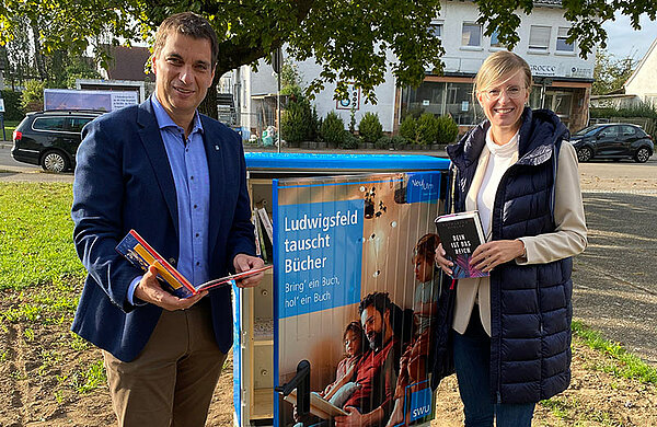 Oberbürgermeisterin Katrin Albsteiger und SWU-Geschäftsführer Klaus Eder vor dem Bücherschrank in Ludwigsfeld.