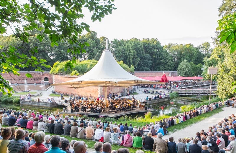 Konzert auf der Veranstaltungsbühne vor vollbesetzten Publikumrängen im Neu-Ulmer Glacis-Park