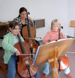Lehrerin mit zwei Kindern beim Musikunterricht (Streichinstrumente)
