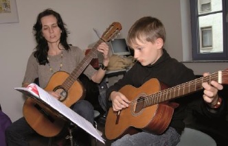 Lehrerin mit Schüler beim Gitarre spielen