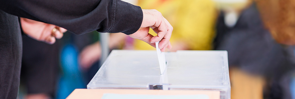 Ein Stimmzettel wird in eine Wahlurne geworfen