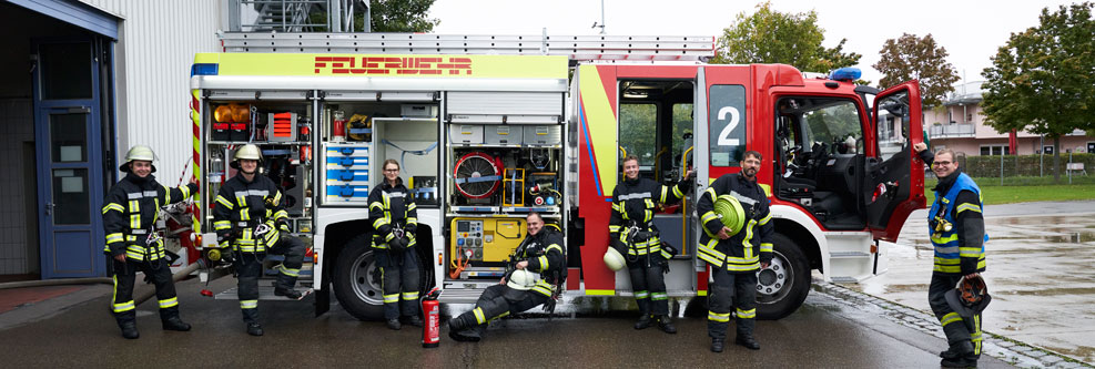 Feuerwehr-Kameradinnen und Kameraden vor einem Löschfahrzeug der Feuerwehr