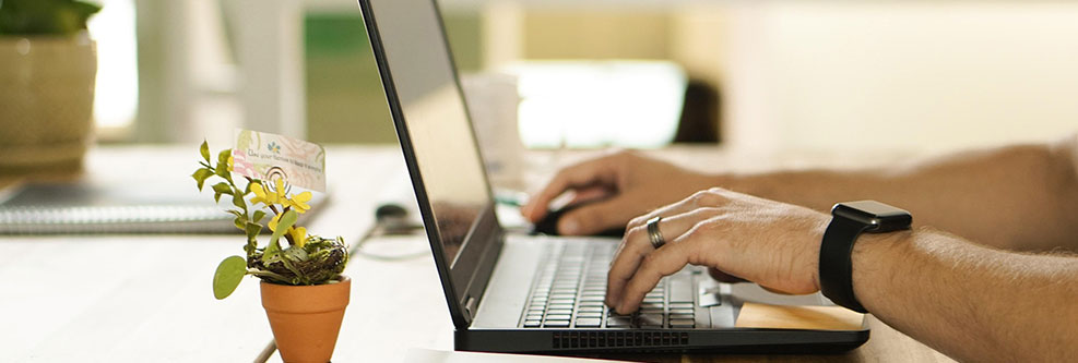 Person tippt auf einem Laptop an einem Schreibtisch