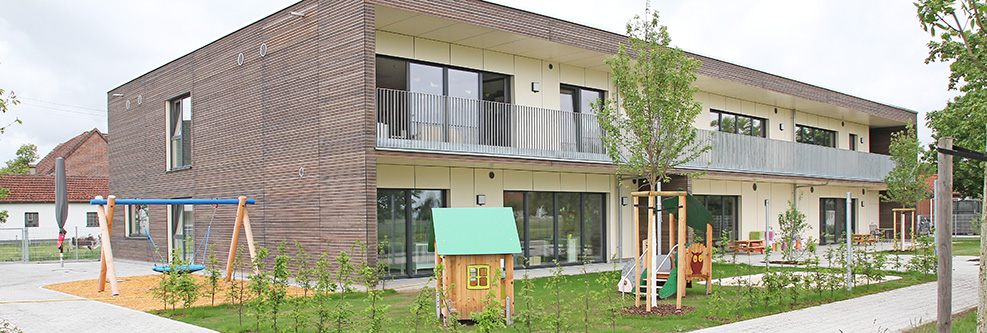 Außenansicht des Kinderhauses Kunterbunt mit Garten und Kinderspielplatz