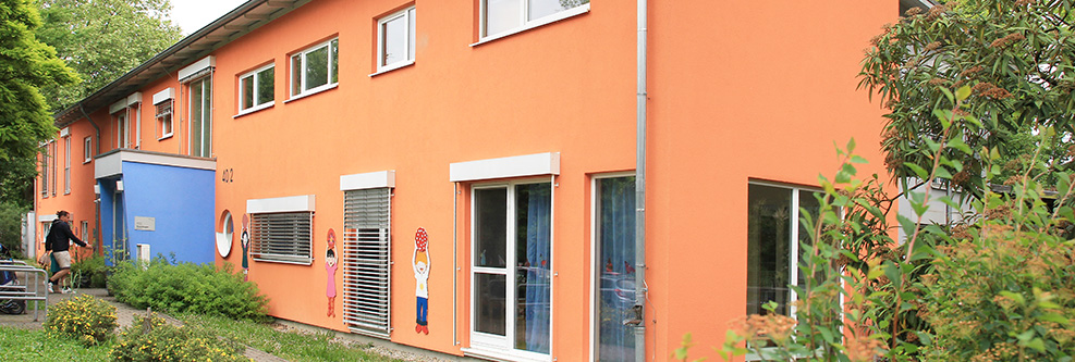 Außenansicht des Kinderhauses Kunterbunt mit Garten und Kinderspielplatz