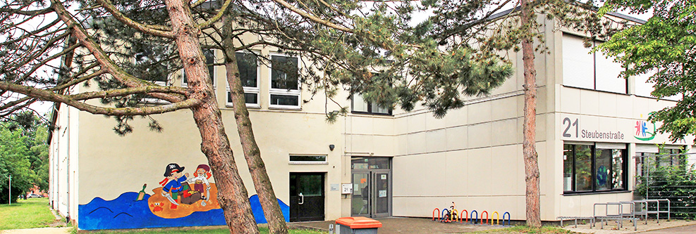 Außenansicht der Kita mit großen Bäumen davor