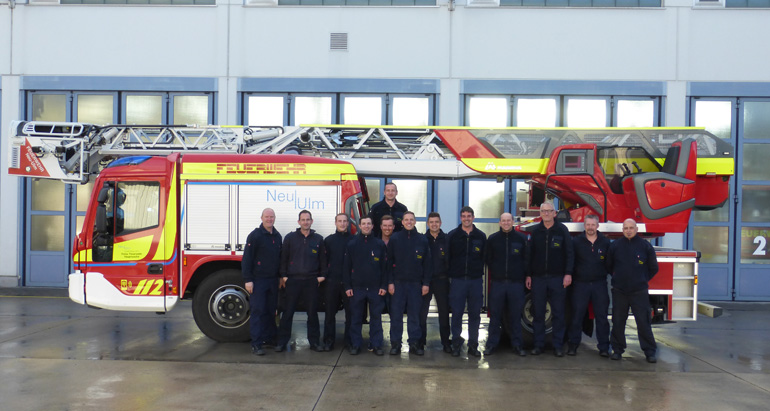 Gruppenfoto mit den den Mitarbeitern vor einem Feuerwehrfahrzeug