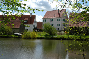 Höfe, Gärten und Häuser des Weilers Tiefenbach, davor ein Fluss