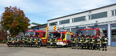 Gruppenfoto mit Feuerwehrleuten vor Feuerwehrfahrzeugen
