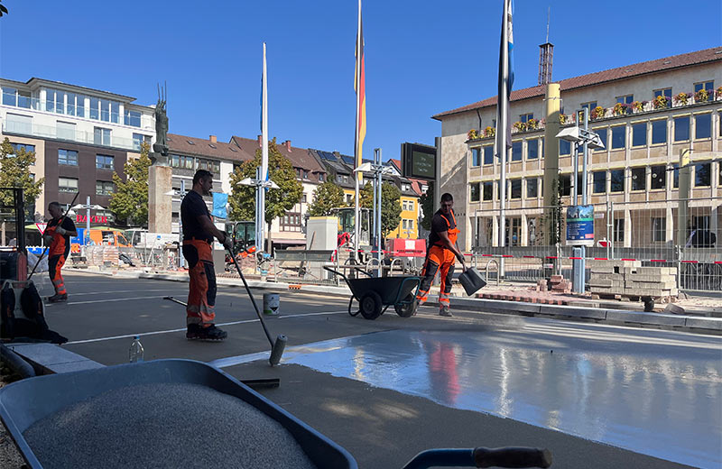 Straßenbauarbeiter bringen den Belag auf der Ludwigstraße auf.