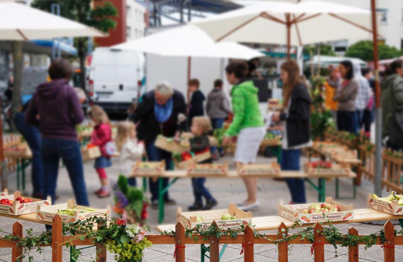 Kinder gehen mit Einkaufskörben auf dem "Markt der Zwerge" einkaufen, im Vordergrund Obstkisten