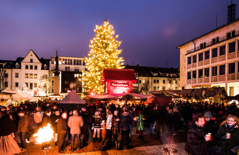 Mitteltalterlicher Weihnachtsmarkt auf dem Neu-Ulmer Rathausplatz mit Weinachtsbaum, Marktständen, Feuerschalen und Besuchern