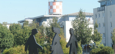 Foto von drei Skulpturen, im Hintergrund der Wasserturm im Wiley