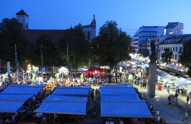 Der Rathausplatz und die Augsburger Straße bei Nacht mit zahlreichen Ständen und Festbesuchern