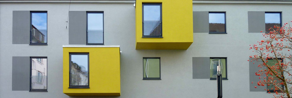 Graue Hausfassdade mit zwei gelben Erkern