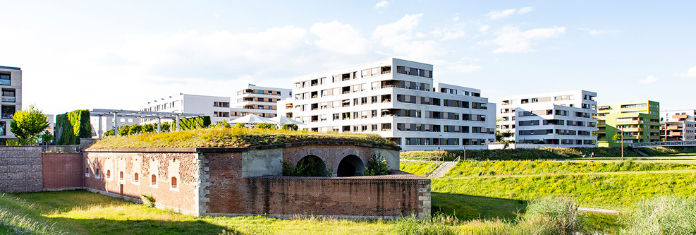 Das Festungsbauwerk Caponniere 4 in Neu-Ulm, dahinter ein modernes Wohngebiet